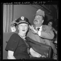 Comedian Jackie Gleason placing conductors hat on reporter Hedda Hopper during train junket named "The Great Gleason Express," in Los Angeles, Calif., 1962