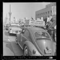 View looking past John Birch Society placard at demonstrators picketing Yugoslavia's President Tito's visit to Los Angeles, Calif., 1963