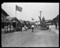 Visitors to the Los Angeles County Fair stroll along a midway lined by livestock stables, Pomona, 1930