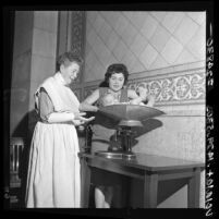 Helen Wolfe, Los Angeles Health Dept. director of nursing, helping weigh a baby, Los Angeles, 1964