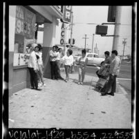 Teenagers hanging out on street corner because of closure of anti-poverty Summer Teen Program in Wilmington, Calif. , 1965