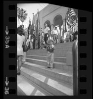 Daryle Klein, 3, waving flag as color guard stands on steps of city hall during POW/MIA demonstration in Los Angeles, Calif., 1973