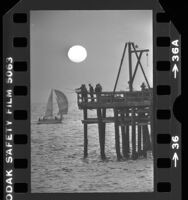 Fishermen on Redondo Beach Pier with sunset behind them, Calif., 1979