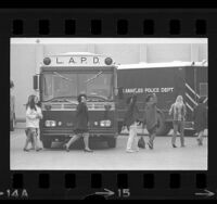 San Fernando Valley State students leaving police bus, three giving Black Power salute, 1969