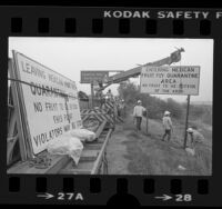 Caltrans workers erecting sign reading "Entering Mexican Fruit Fly Quarantine Area" along Long Beach Freeway, South Gate (Calif.), 1983