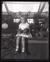 A young girl holding two large avocados, Orange County, 1928