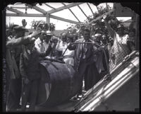 Crowd of people witnessing police returning wine barrels to Tony Panzich's wine cellar during Prohibition, Los Angeles, 1929