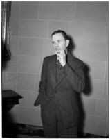 Thomas W. Hall stands by a staircase wearing a suit, Los Angeles, 1930s