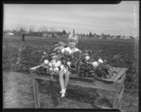 Young girl sits amongst the harvest from a community garden, circa February 1934