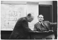 Murder suspect Robert S. James sitting on the witness stand with a plan of his house behind him, Los Angeles, 1936