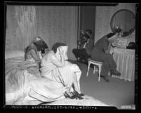 Three women covering their faces as photographer takes picture at raid on house of prostitution in Los Angeles, Calif., circa 1948