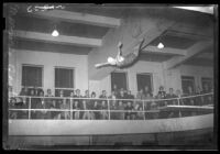 Springboard diver Marjorie Gestring leaping from the board in front of a crowd of spectators, Los Angeles