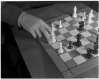 Close-up of a chess board and a player's hand moving the white queen, Los Angeles