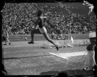 Jesse Owens competes in a broad jump event at a track meet, Los Angeles, 1930s