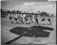 Football players on the Manual Arts High School team run drills during practice, Los Angeles, circa 1937