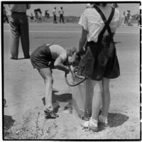 Two girls take a drink of water from a hose during a soap box derby race, Los Angeles, 1946