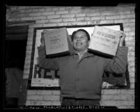 Navajo man carrying boxes of food received from Navajo Relief, Calif., 1947