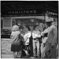 Woman and man talking to truant teenagers standing outside a jewelry store, Los Angeles, March 1946