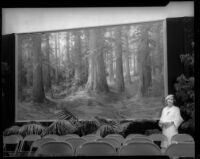 Martella Lane, painter, poses with painting of California Redwoods, [1925?]