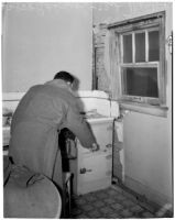 Daily News reporter Brooks Barnes pointing at oven in an apartment where a gas explosion occurred, Los Angeles, 1940