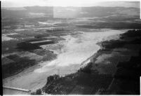 Aerial view of flood water moving down a river and destroying crops in North Hollywood after a major flood, Los Angeles, 1938