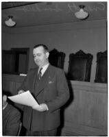 Political figure Everett Sanders stands holding a sheet of paper, Los Angeles