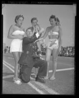Man wearing gag thumb with three bathing beauties, Long Beach, Calif., 1949