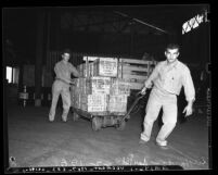 Two longshoremen hauling wooden crates at Los Angeles Harbor; San Pedro, 1939