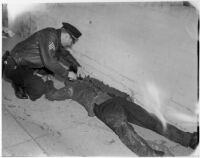 Fellow firefighter attends to Capt. Noble Swanson, who was injured when a section of roof caved in during a fire at the Melody Lane Café on Wilshire Blvd., Los Angeles, 1947