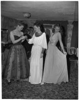 Three models in long dresses in their dressing room preparing for a fashion show, Los Angeles