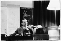 Murder suspect Robert S. James sitting on the witness stand with a plan of his house behind him, Los Angeles, 1936