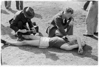 Sports officials examining a USC track athlete for injury, Los Angeles, 1937