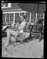 Dorothy McGrath lounging on a Los Angeles beach while using "Walkie Talkie" radio set, circa 1947