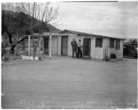 Two unidentified men stand outside the deserted Palm Springs cabin where Betty Hardaker hid after murdering her daughter Geraldine Hardaker, Los Angeles, 1940