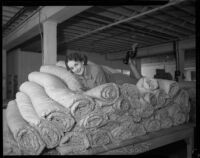 Rosalind Roennburg poses on a pile of mattresses at a factory, Los Angeles, 1935