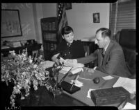 Film actress Anna May Wong looking over an extortion letter with District Attorney Buron Fitts, Los Angeles, 1937