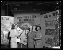 Three women standing before Alert America (civil defense) posters in Los Angeles, Calif., 1952