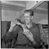 Soldier feeding a puppy from a baby bottle during the Army-Navy maneuvers off the coast of Southern California in late 1946