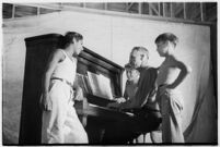 Boys gathered around piano and pianist, taking part in a free summer camp organized by Los Angeles Sheriff Eugene Biscailuz. Circa July 1937