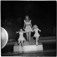 Woman and two little girls model swim suits in a fashion show that featured local designers, Los Angeles, September 1946