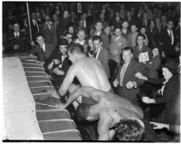 Wrestlers Gino Garibaldi and Ernie Dusek falling out of the ring during at match a Olympic Auditorium, Los Angeles, October 6, 1937