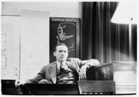 Murder suspect Robert S. James sitting on the witness stand with a plan of his house behind him, Los Angeles, 1936