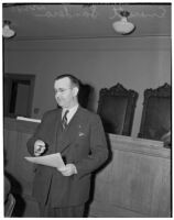 Political figure Everett Sanders stands holding a sheet of paper, Los Angeles