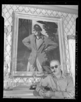 Director John Ford standing before portrait of himself and Academy Award statue, circa 1946