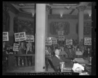 Protesters with signs in gallery of Los Angeles County Supervisors hearing over eminent domain for construction of Harbor Freeway, Calif., 1947