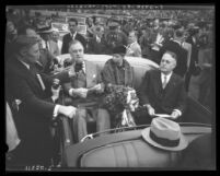 President Franklin D. Roosevelt and wife Eleanor seated in open car talking to reporters on visit to Los Angeles, Calif., 1935