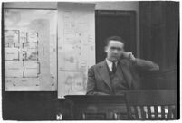 Murder suspect Robert S. James sitting on the witness stand with a map of his house behind him, Los Angeles, 1936