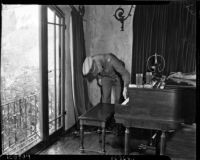 Capt. J.H. Carter inspects a piano bench in the home of Paul A. Wright, where Wright fatally shot his wife and best friend, Glendale, November 10, 1937