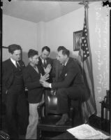 Detective Lieutenant Ray Giese, Los Angeles County District Attorney Buron Fitts, and two unidentified men examine the hands of Thomas Edward Dugger who was on trial for assaulting three women, Los Angeles, 1935-1936