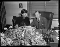 Film actress Anna May Wong looking over an extortion letter with District Attorney Buron Fitts, Los Angeles, 1937